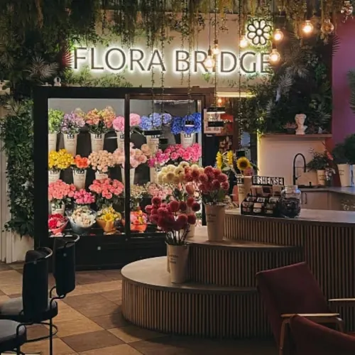 The Flora Bridge flower shop in Istanbul with its illuminated sign and a cooler full of fresh stems