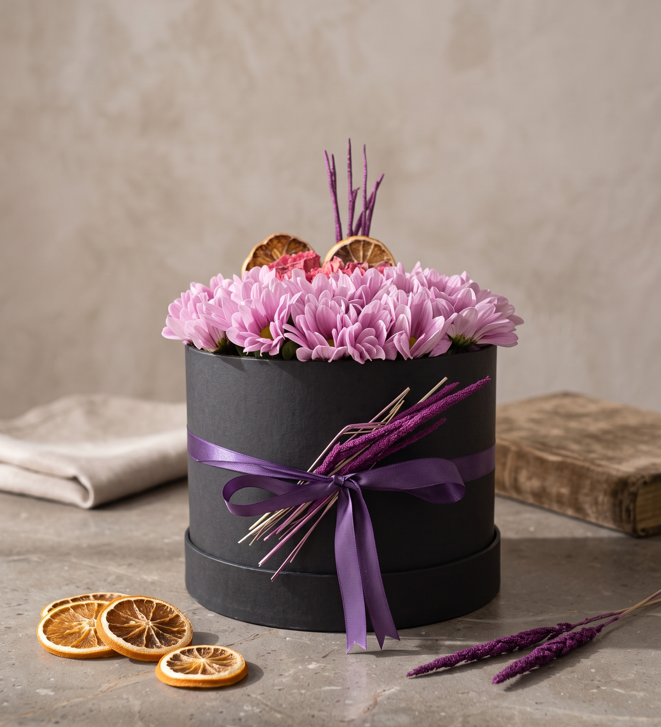 35 Pink Daisies & Rose in a Black Box, Thirty-five pink spray daisies packed dome-full around a dozen pink garden roses, finished with dried lemon slices and a purple ribbon in a sleek black box.