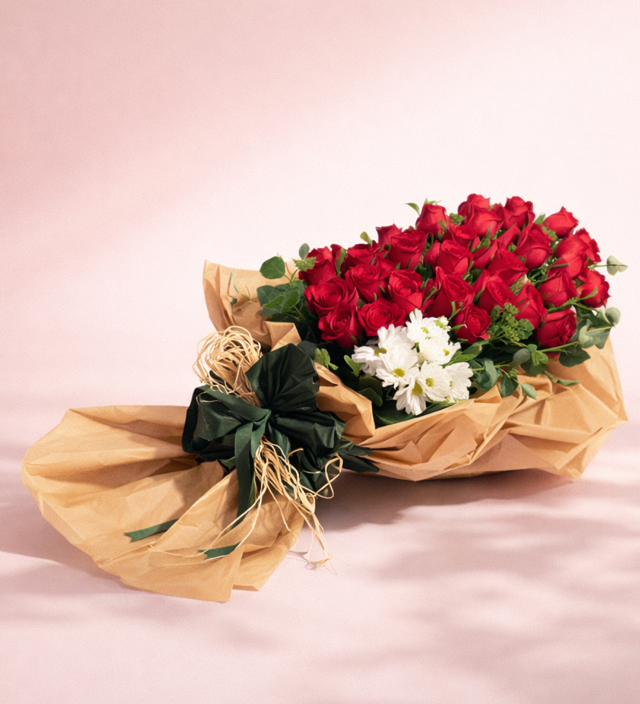 41 Roses Rouges & Marguerites Blanches en Emballage Kraft, Quarante et une roses rouges avec des marguerites blanches et de l'eucalyptus, enveloppées de papier kraft et d'un papier bicolore vert-marron avec un ruban vert foncé, d'environ 50 à 60 cm de haut.