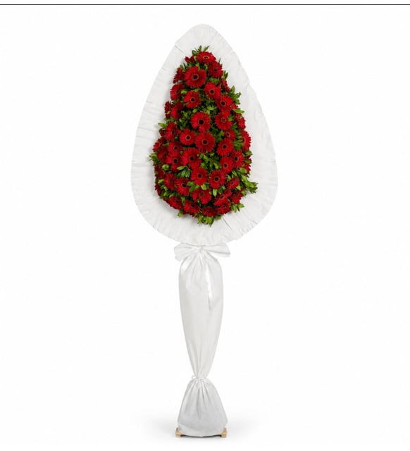 Couronne Funéraire à Un Étage, 60 Gerberas Rouges, Une couronne funéraire classique de 2 mètres : soixante gerberas rouges en forme de goutte sur une armature de satin blanc plissé, sur un haut pied habillé, pour des funérailles à Istanbul.