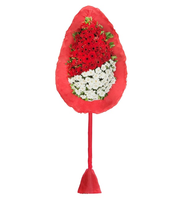 Einstöckiger Trauerkranz mit Roten und Weißen Gerbera, Ein 2 Meter hoher Trauerkranz mit roten Gerbera oben und weißen Gerbera unten, gerahmt von rotem Krepppapier auf einem hohen umhüllten Ständer, für eine Beerdigung in Istanbul.