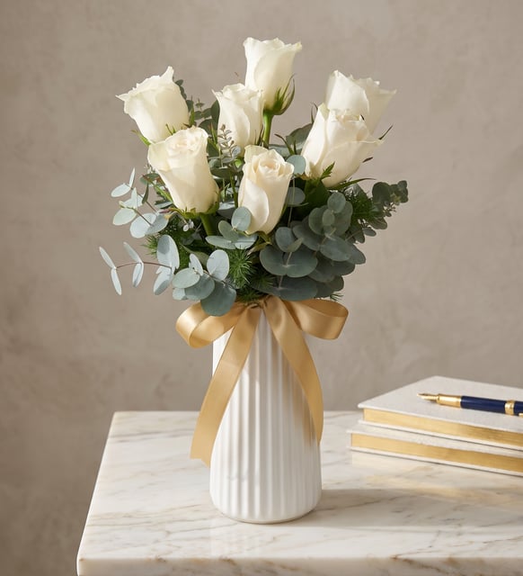 7 weiße Rosen in einer weißen Rillenvase, Sieben weiße Rosen mit Eukalyptus in einer perlweißen Rillenvase, mit goldgesprenkeltem Band.