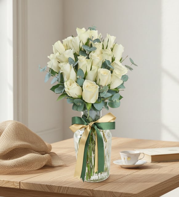 21 weiße Rosen in einer gestreiften Glaskaraffe, Einundzwanzig weiße Rosen mit frischem Eukalyptus in einer gerillten Karaffenvase aus Glas, mit dunkelgrünem und goldgesprenkeltem Band.