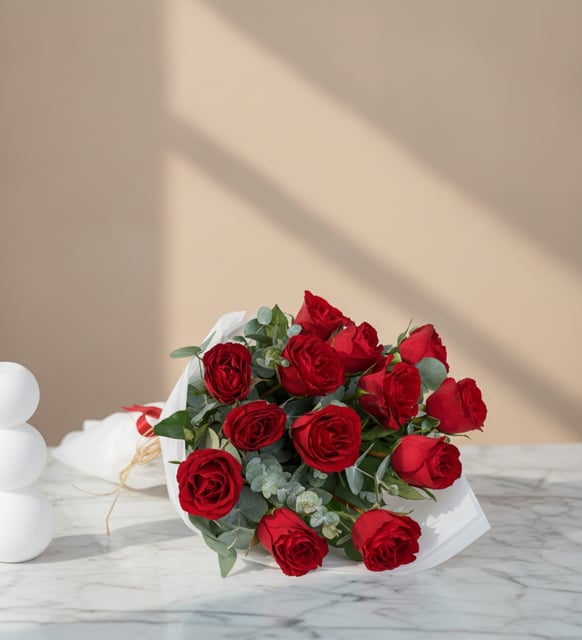 Strauß mit 13 roten Rosen, Dreizehn rote Rosen mit Eukalyptus zu einem vollen, runden Strauß in weißem Papier gebunden.
